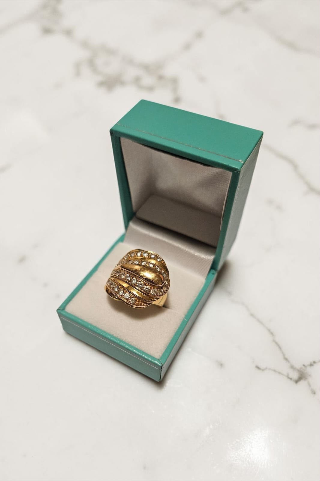 Layered gold ring with stones in a green jewelry box